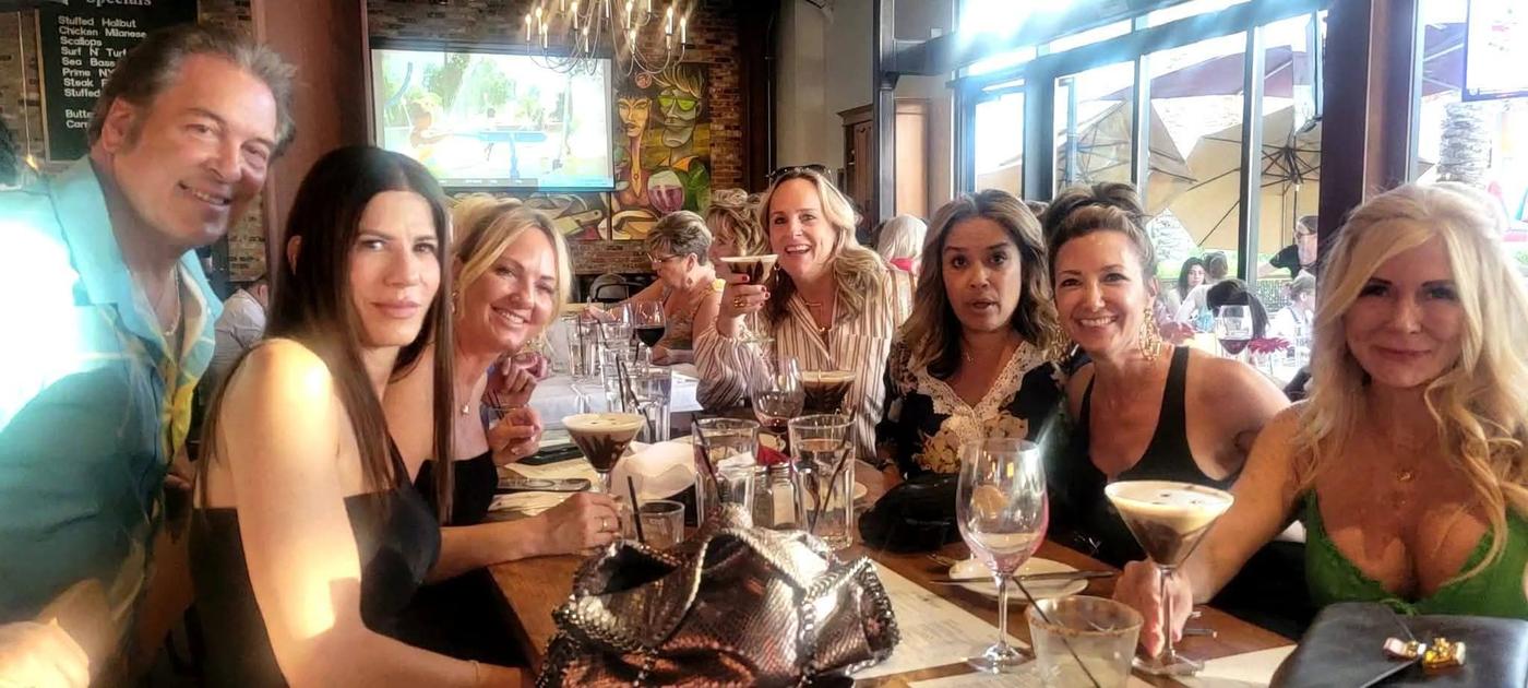 A group of friends smiling together around a dinner table