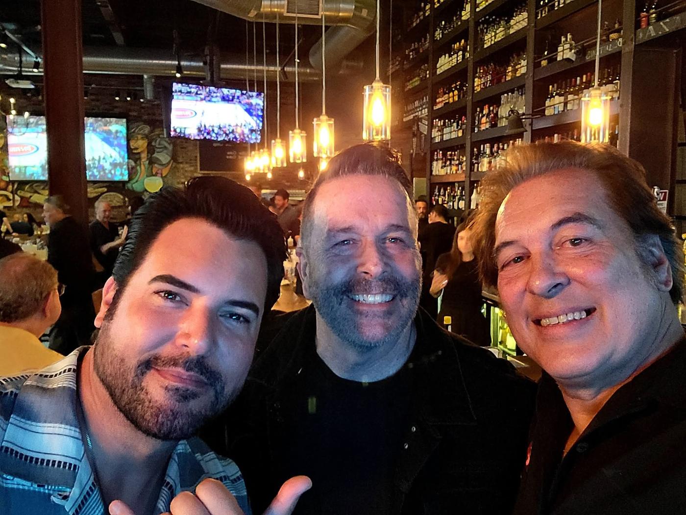 Craig smiling for a photo with two friends